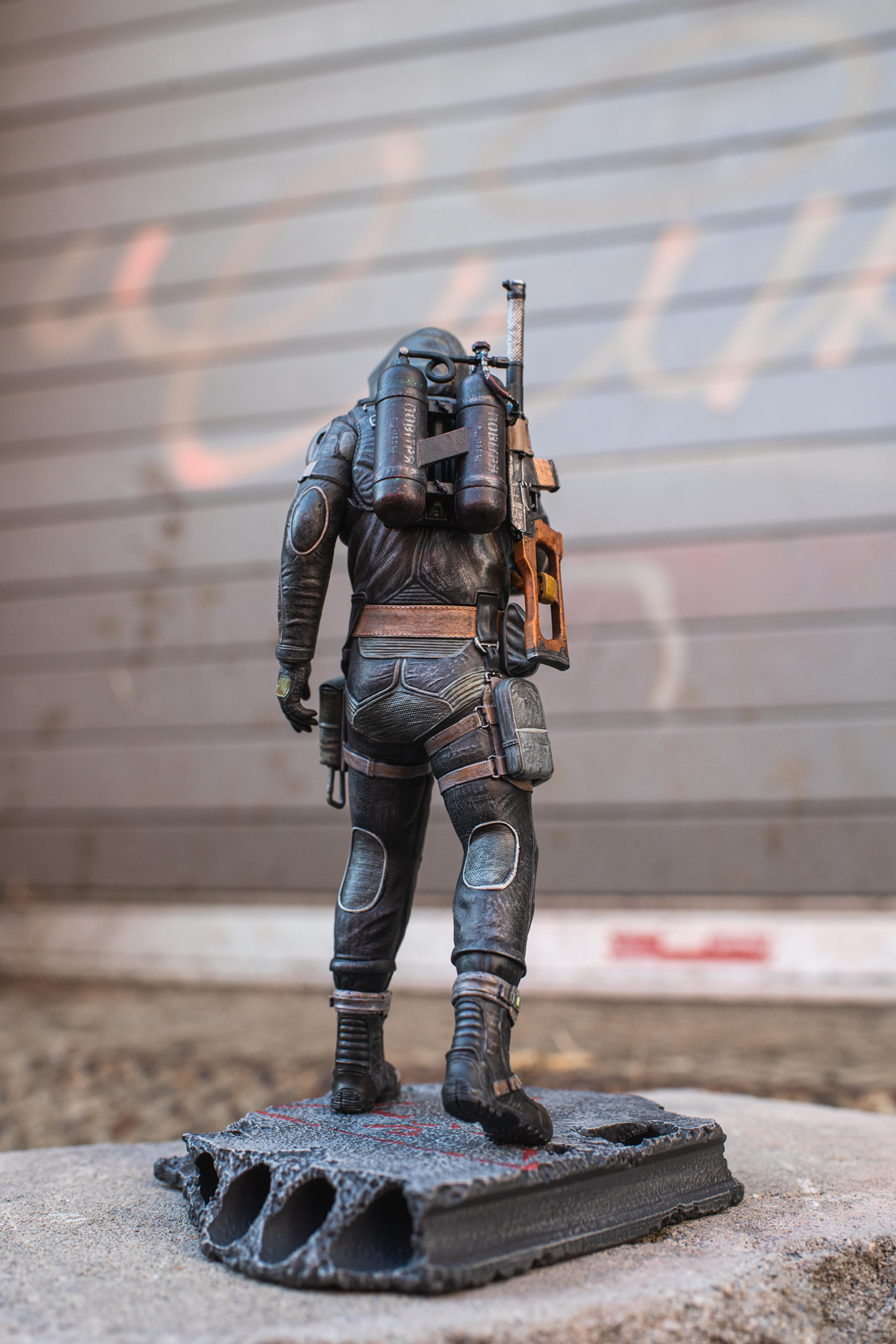 Statue of a character in futuristic armor with a weapon on a concrete surface.