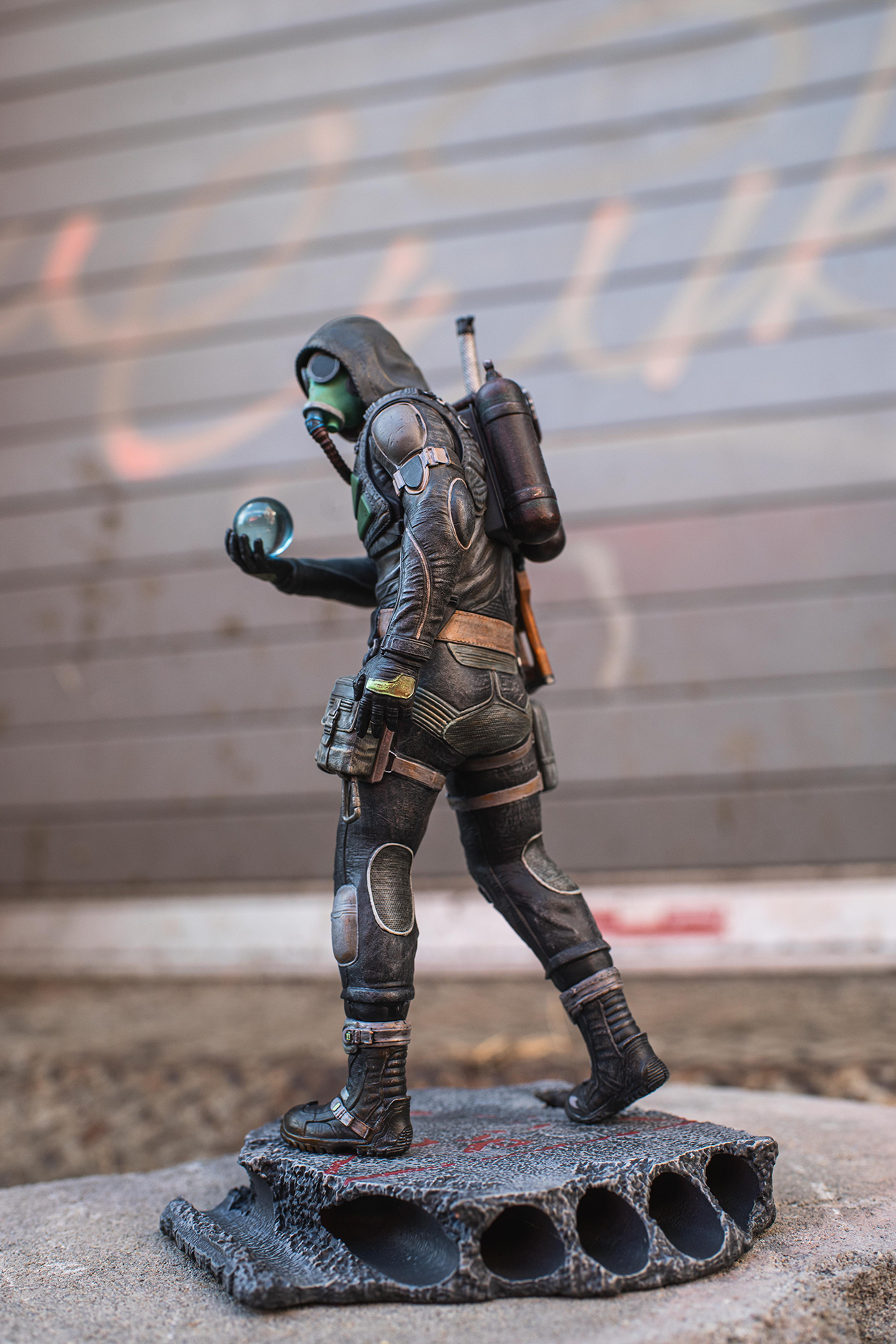 Figurine of a character in a futuristic suit with a backpack on a concrete surface.