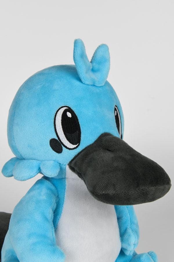 Image shows Temtem Platypet Plush facing front at a left angle. Product has either side of its head having three round tufts of fur with the middle tuft being bigger than the outer two. 
